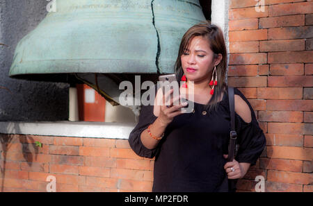 Concerned Asian woman from the Philippines talking on her smartphone outdoors. Stock Photo