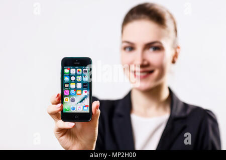 Young woman holds black Apple iPhone 5 display in hand. Stock Photo