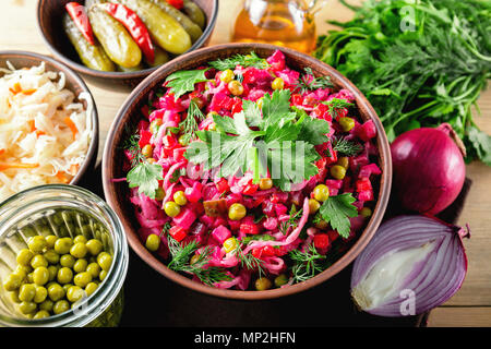 Vinaigrette salad with boiled vegetables, pickled cucumbers, sauerkraut and canned green peas in a clay bowl. Traditional Russian snack. Vegetarian fo Stock Photo
