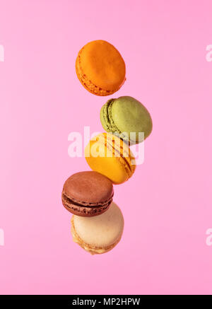 Colored french macarons flying in freeze motion. Concept of flying food isolated on pink background. High resoution image Stock Photo