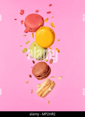 Colored french macarons flying in freeze motion. Concept of flying food isolated on pink background. High resoution image Stock Photo