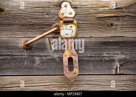Close up old rusty handle and hinge on grey wooden texture Stock Photo