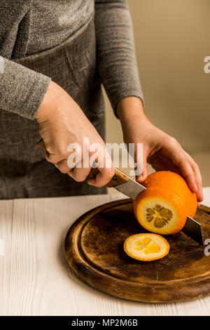 Close up female hands slicing orange with knife into pieces Stock Photo