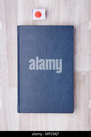 Flat lay of blue textured notepad with Japanese flag on toothpick as bookmark. Stock Photo