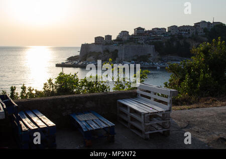 Cozy bar with the beautiful sunset view on sea and Stadi Grad - old town of Ulcinj at twilight scene. Coast of Adriatic sea. Montenegro. Stock Photo