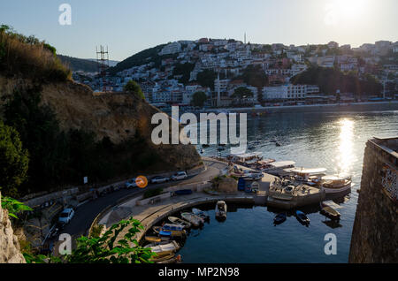 Small fishing boats marina with round pier. Wide angle shot with a city and central beach Mala Plaza on background. Ulcinj, Montenegro. Stock Photo