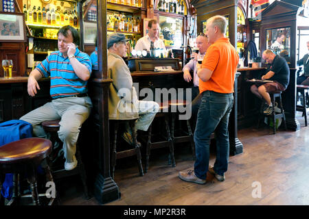 Man talking on his mobile phone and friends chatting in front of the pub bartender, The Palace Bar, Temple Bar, Dublin, Ireland, Europe Stock Photo