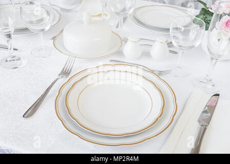 Beautifully decorated table with empty white plates, glasses, cutlery and flowers on luxurious tablecloths Stock Photo
