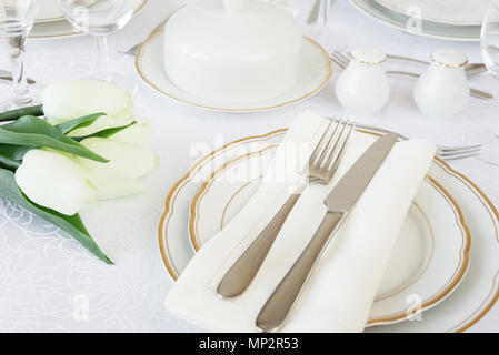 Beautifully decorated table with empty white plates, glasses, cutlery and flowers on luxurious tablecloths Stock Photo