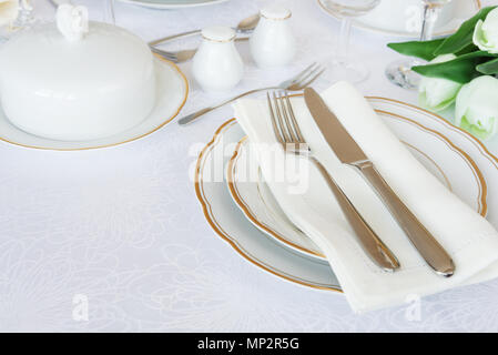 Beautifully decorated table with empty white plates, glasses, cutlery and flowers on luxurious tablecloths, with copy-space Stock Photo