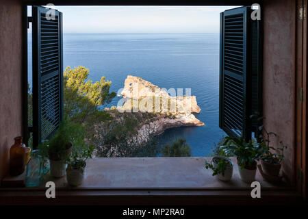 View through an open window of the Punta de  Sa Foradada Peninsula in Deia, Mallorca. Stock Photo