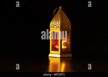 Traditional ornamental arabic lantern with a burning candle in dark studio setting. Festivel greeting card for Ramadan Kareem and Ramadan Mubarak. Dub Stock Photo