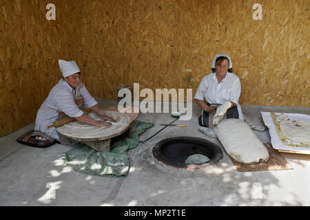 Two women make lavash (a traditional flatbread) by rolling out the dough, then baking in a tandoor oven, Garni, Armenia Stock Photo