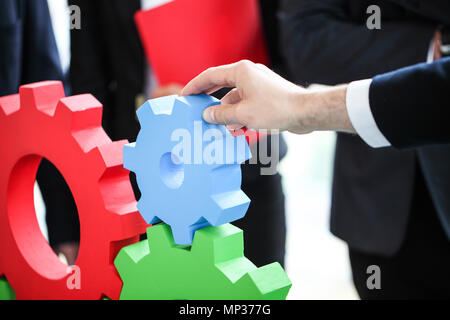 Business people assembling cogwheels, teamwork concept Stock Photo