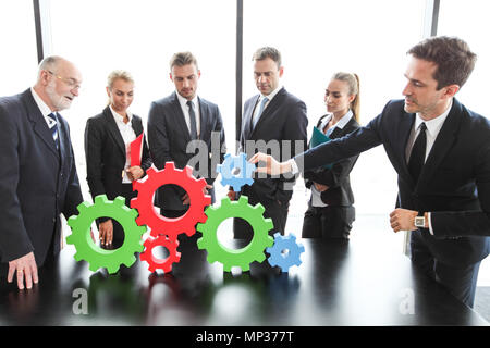 Business people assembling cogwheels, teamwork concept Stock Photo