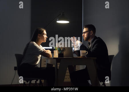 Colleagues discussing business strategies in office at night Stock Photo