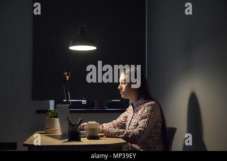Tired female browsing information at laptop working late hours Stock Photo