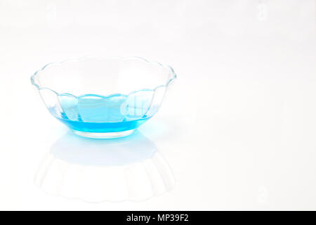 Crystallizing dish (crystallising) of copper sulfate solution (copper chloride) blue liquid isolated on white reflective background with shallow depth Stock Photo
