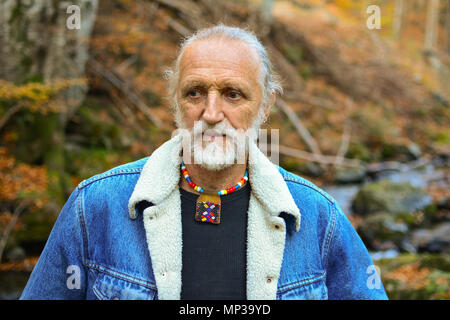 Good looking elderly man outdoors, walking along mountain creek, through colorful autumn forest Stock Photo