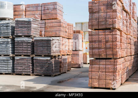 pallets with bricks in the building store. Racks with brick. Masonry, stonework. Several pallets with concrete brick stacked on top of each other in d Stock Photo