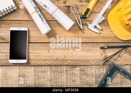 Architect workplace. Smart phone with black blank screen, project construction blueprints and engineering tools on wooden desk, copy space, top view Stock Photo