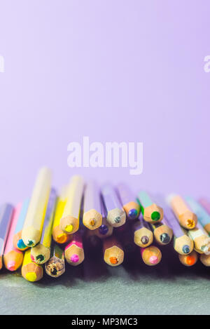 Very used pencils of different colors isolated on a lilac background. Concept of spare to buy new ones Stock Photo