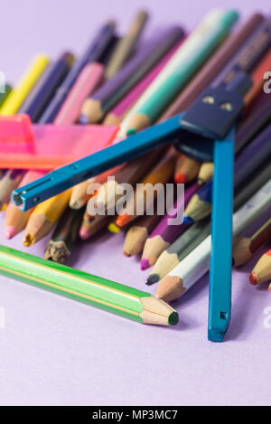 close-up of old broken compass on old colored pens isolated on a lilac background. Concept of spare to buy new ones Stock Photo