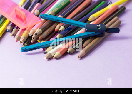 close-up of old broken compass on old colored pens isolated on a lilac background. Concept of spare to buy new ones Stock Photo