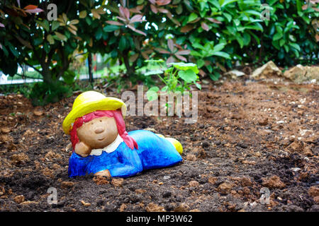 Garden gnome, dwarf on soil, colorful girl as gardener Stock Photo