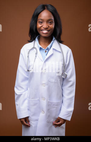 Young beautiful African Zulu woman doctor against brown backgrou Stock Photo