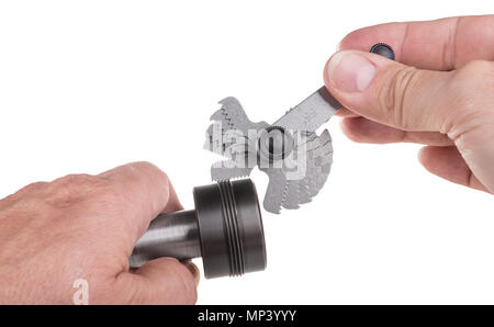 Thread pitch gauge measurement close-up. Detail of machinist's hands, set of threaded gauges and workpiece. Steel jig, measuring hand tool. Isolated. Stock Photo