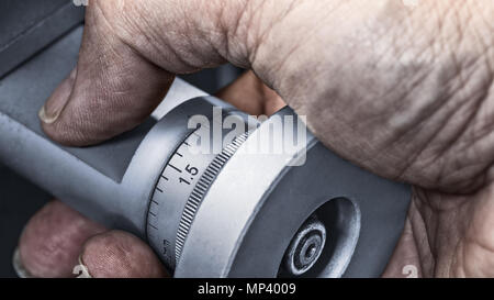 Control knob of machine tool in detail. Close-up of dirty hand on metal wheel with vernier scale for accurate measurement. Idea of precise machining. Stock Photo