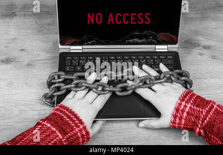 Close-up of hands on laptop secured in old rusty chains. No access in red color. Black and white wooden background. Idea of censorship, backup, GDPR. Stock Photo