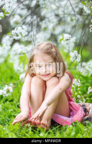 Happy little girl in cherry blossom garden Stock Photo