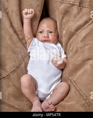 A three week old baby boy looking at the camera with his arm raised up Stock Photo