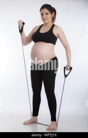 Pregnant woman doing gymnastic exercises on white background Stock Photo