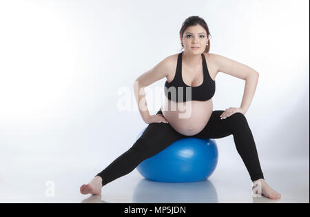 Pregnant woman is doing exercises with gymnastic ball on white background Stock Photo