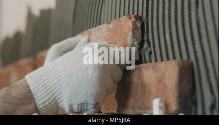 closeup worker applying brick cuts tile to the wall Stock Photo