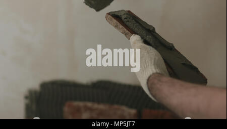 closeup worker applying concrete glue to brick cuts tile Stock Photo