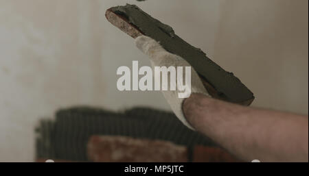 closeup worker applying concrete glue to brick cuts tile Stock Photo