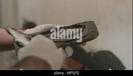 closeup worker applying concrete glue to brick cuts tile Stock Photo