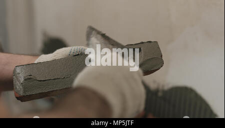 closeup worker applying concrete glue to brick cuts tile Stock Photo