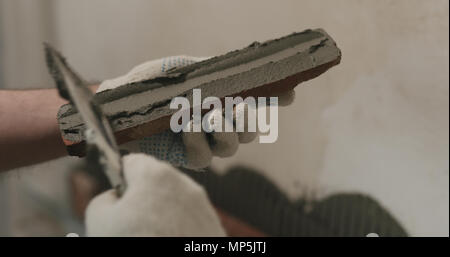 closeup worker applying concrete glue to brick cuts tile Stock Photo