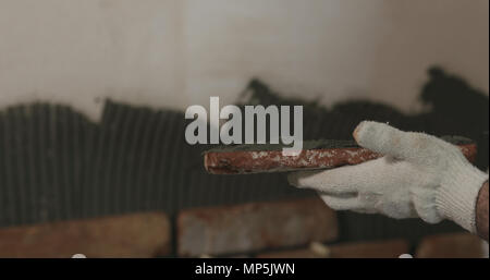 closeup worker applying concrete glue to brick cuts tile Stock Photo