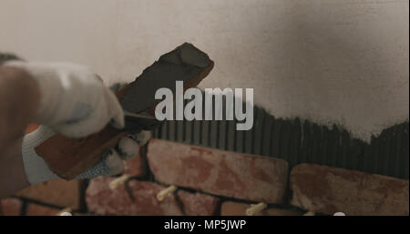 closeup worker applying concrete glue to brick cuts tile Stock Photo