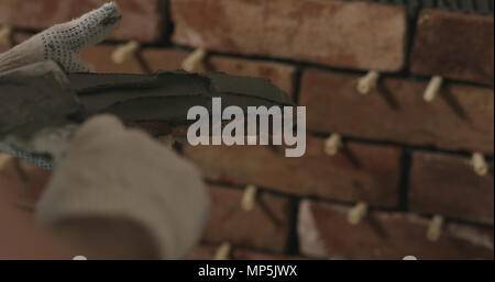 closeup worker applying concrete glue to brick cuts tile Stock Photo