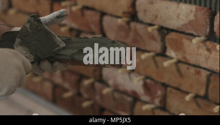 closeup worker applying concrete glue to brick cuts tile Stock Photo