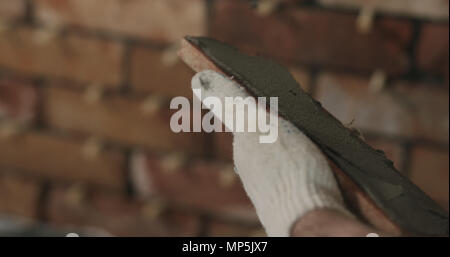 closeup worker applying concrete glue to brick cuts tile Stock Photo