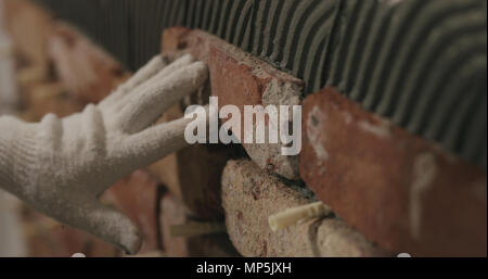 closeup worker applying brick cuts tile on the wall Stock Photo