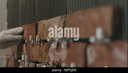 closeup worker applying brick cuts tile on the wall Stock Photo